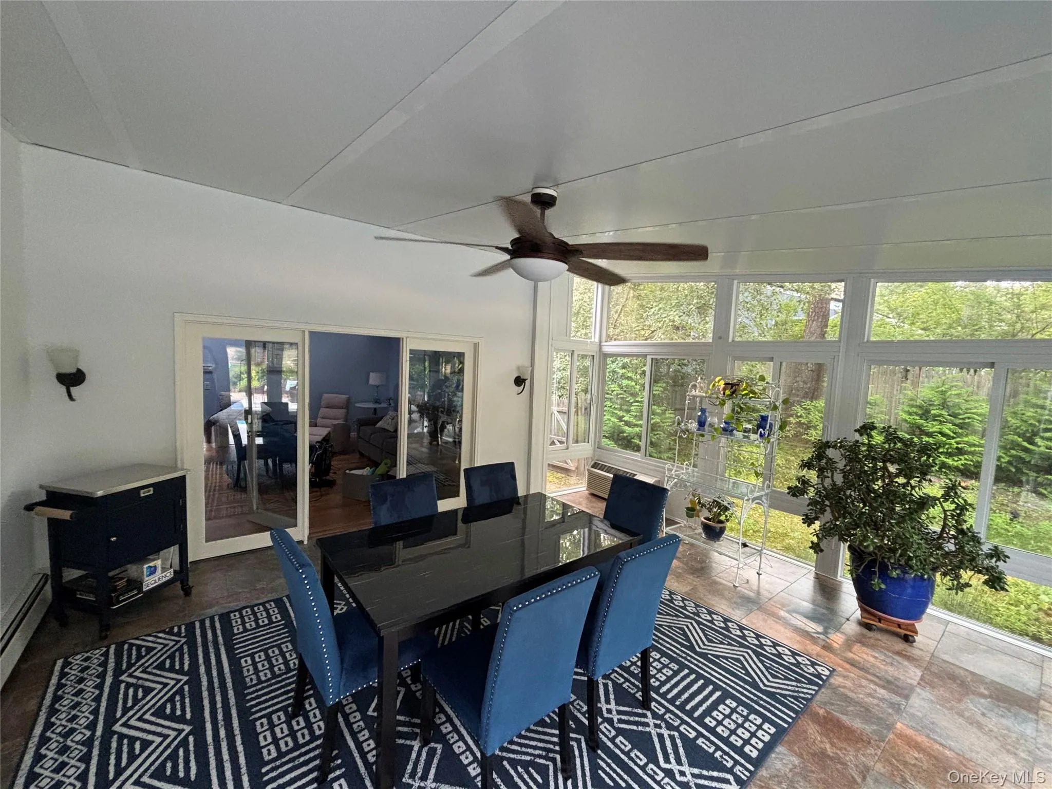 Light-filled Sunroom featuring extensive window-paneled walls, tile flooring, and a ceiling fan with integrated lighting Light-filled Sunroom featuring extensive window-paneled walls, tile flooring, and a ceiling fan with integrated lighting