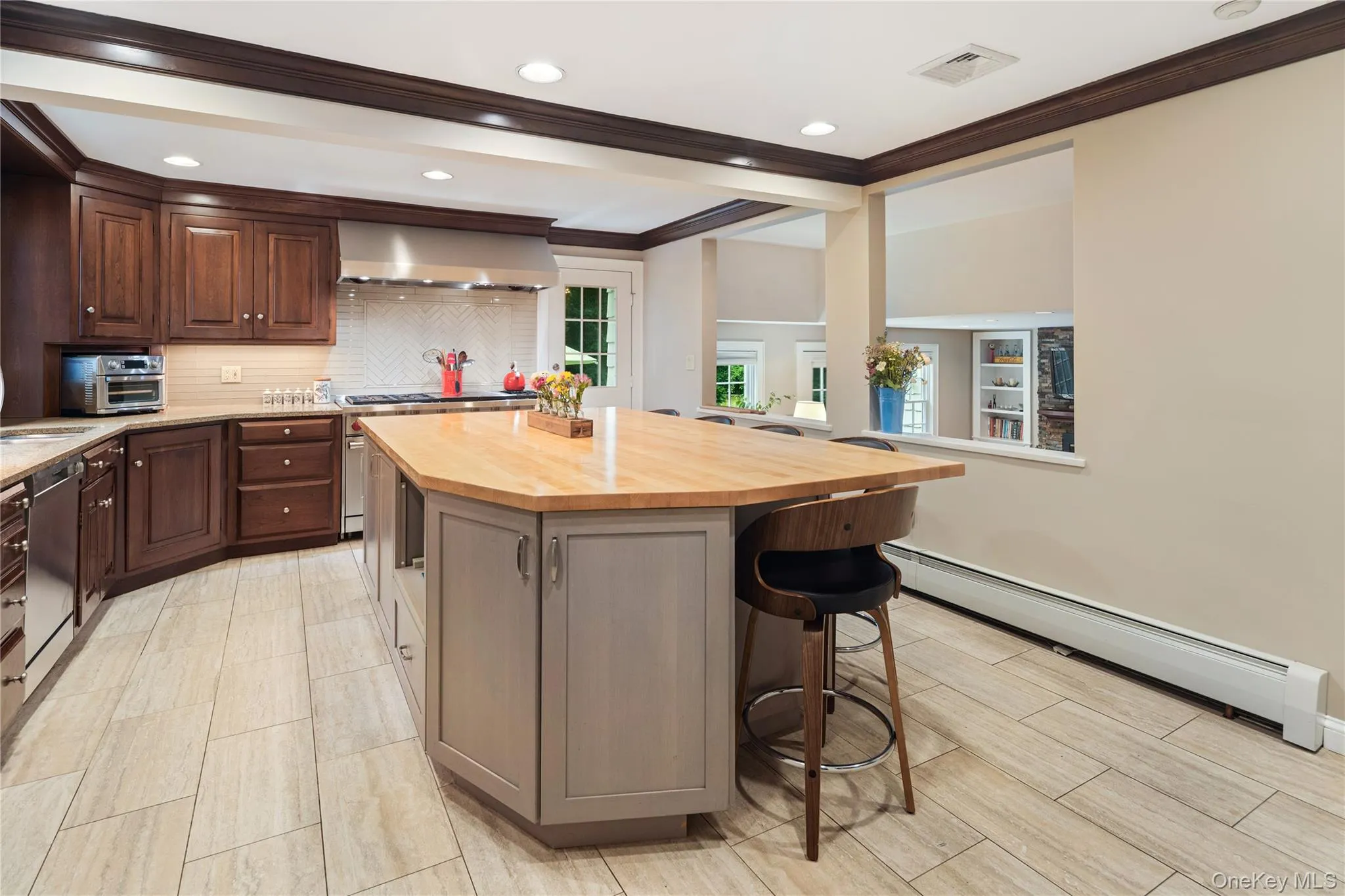 Eat-in kitchen with integral paneled Subzero refrigerator, SS Wolf gas range with double ovens, 6 burners and additional grill and griddle, SS undermount double sink, vent hood with heat lamps, 12x24 tile floor, glass backsplash, granite counters, wood cabinetry with custom pullouts, contrasting expansive center island with butcher block counter and seating, crown molding, double pantry closet, recessed lighting, open to family room Eat-in kitchen with integral paneled Subzero refrigerator, SS Wolf gas range with double ovens, 6 burners and additional grill and griddle, SS undermount double sink, vent hood with heat lamps, 12x24 tile floor, glass backsplash, granite counters, wood cabinetry with custom pullouts, contrasting expansive center island with butcher block counter and seating, crown molding, double pantry closet, recessed lighting, open to family room