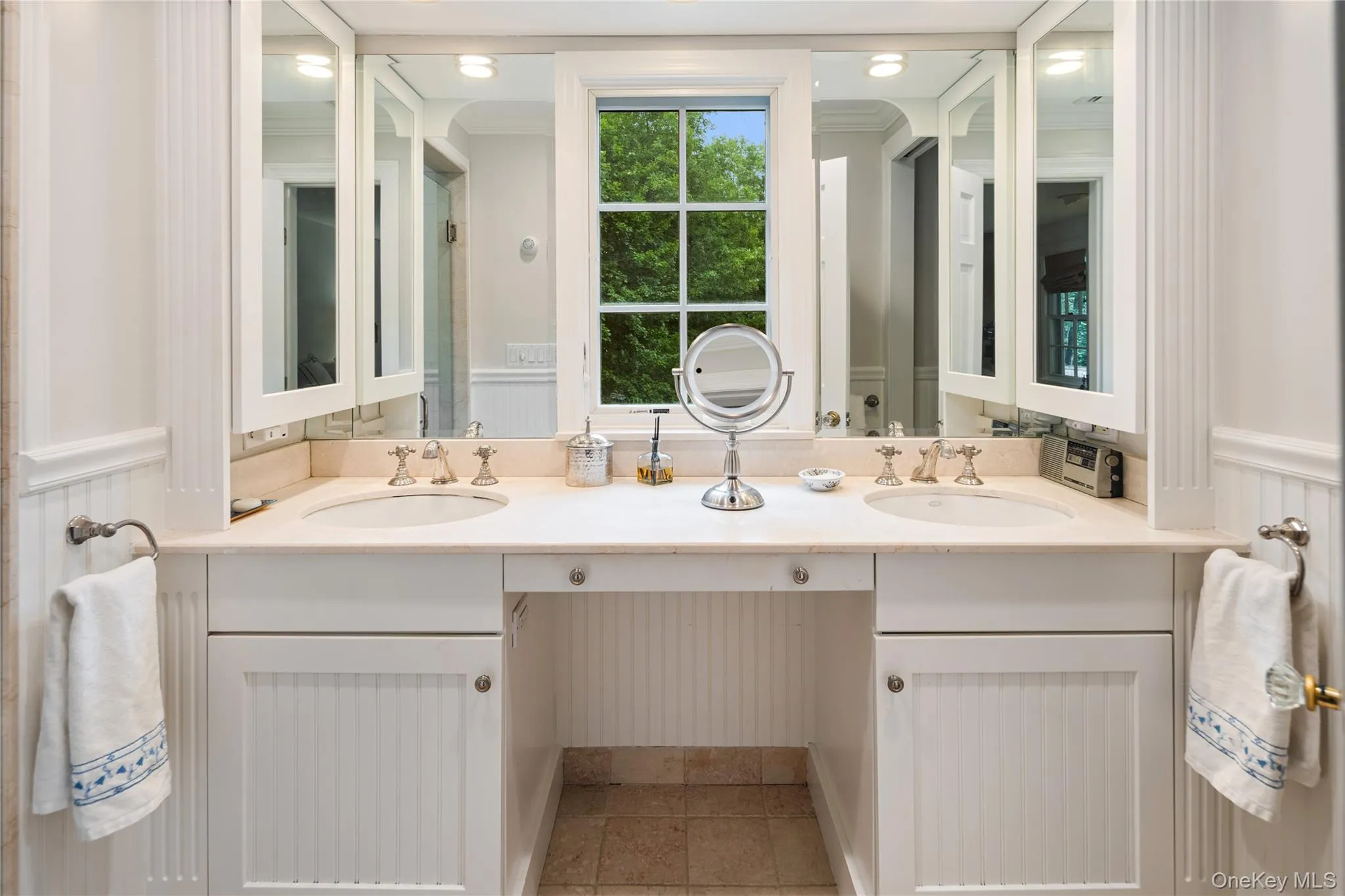 En-suite tumbled marble primary bath with dual sinks, medicine cabinets, oversized walk-in shower, and separate water closet with pocket door for privacy En-suite tumbled marble primary bath with dual sinks, medicine cabinets, oversized walk-in shower, and separate water closet with pocket door for privacy