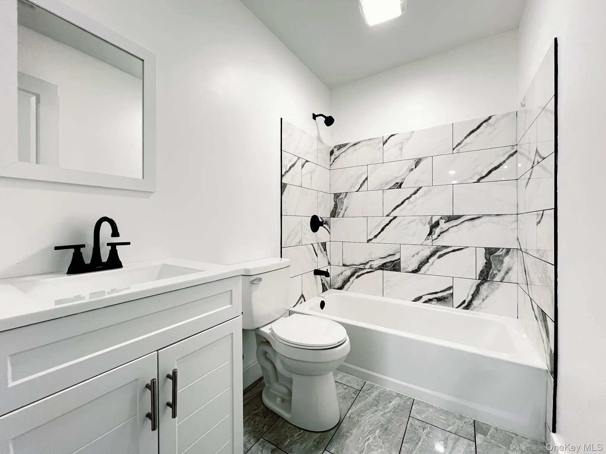 2nd floor full bathroom featuring a white vanity with integrated sink, black matte faucet, and matching framed mirror 2nd floor full bathroom featuring a white vanity with integrated sink, black matte faucet, and matching framed mirror