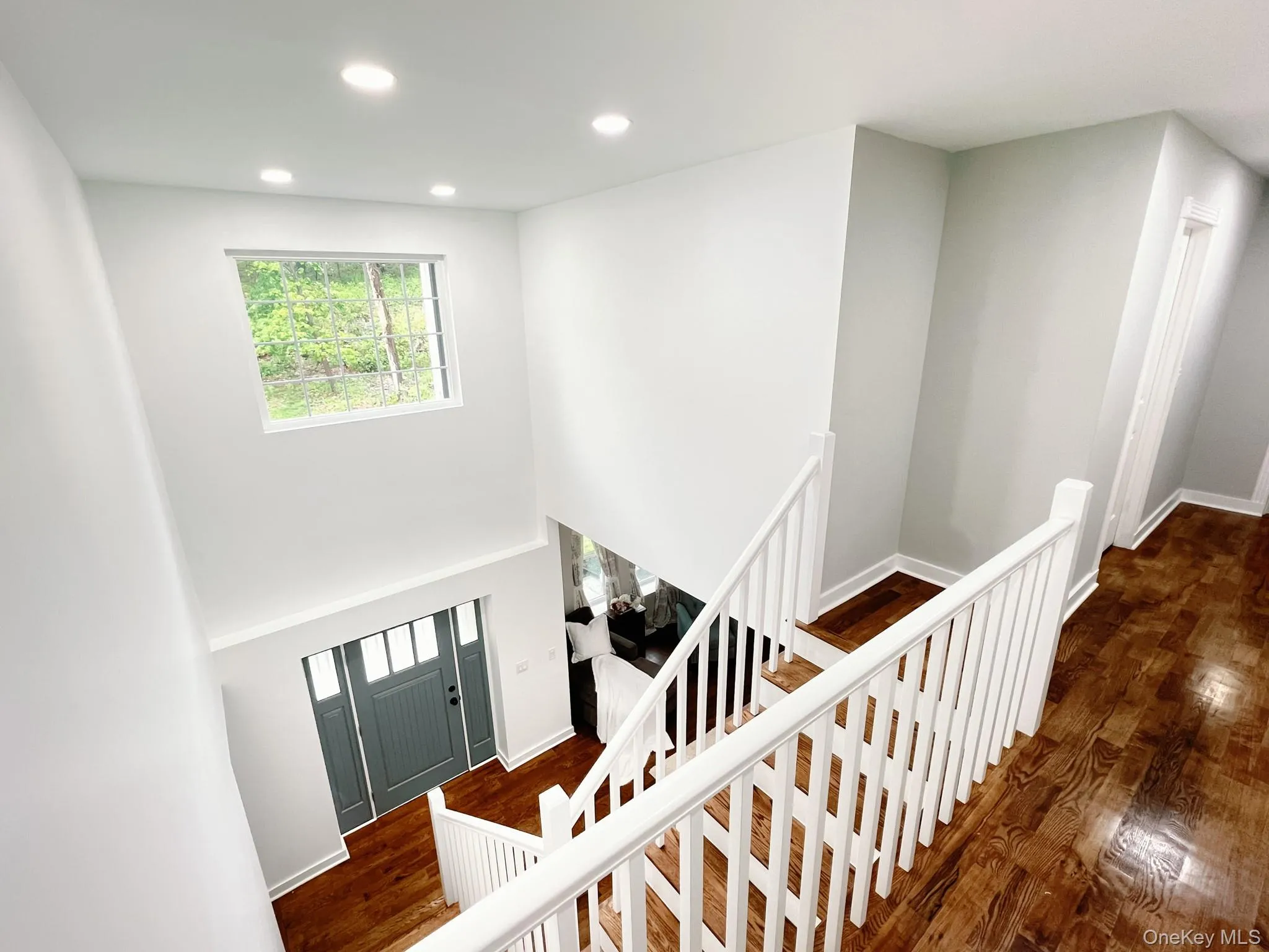 Two-story entry foyer featuring a transom window, dark wood flooring, recessed lighting, and a paneled front door with sidelights Two-story entry foyer featuring a transom window, dark wood flooring, recessed lighting, and a paneled front door with sidelights