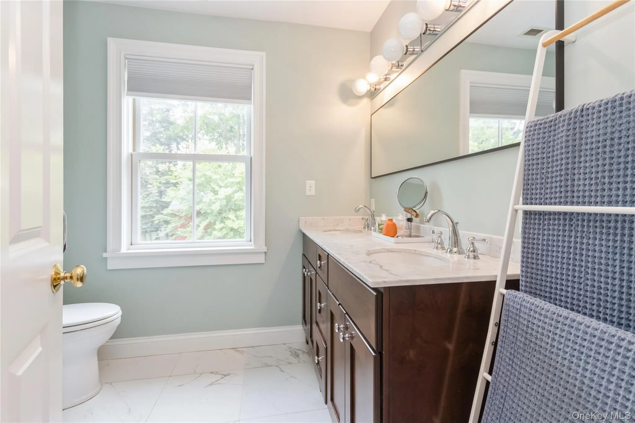 Full bathroom with double vanity and marble look tile flooring Full bathroom with double vanity and marble look tile flooring