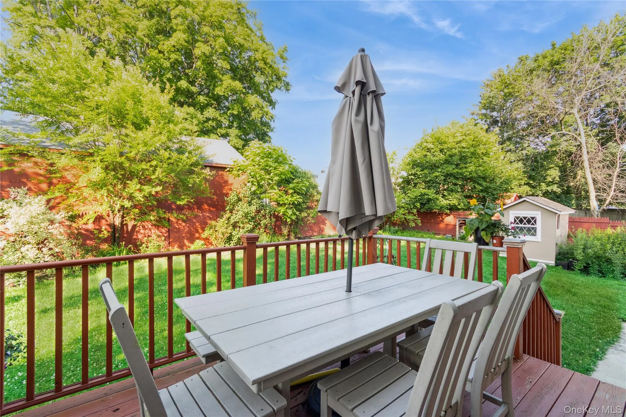 Wooden terrace featuring a lawn, outdoor dining area, and a storage shed Wooden terrace featuring a lawn, outdoor dining area, and a storage shed