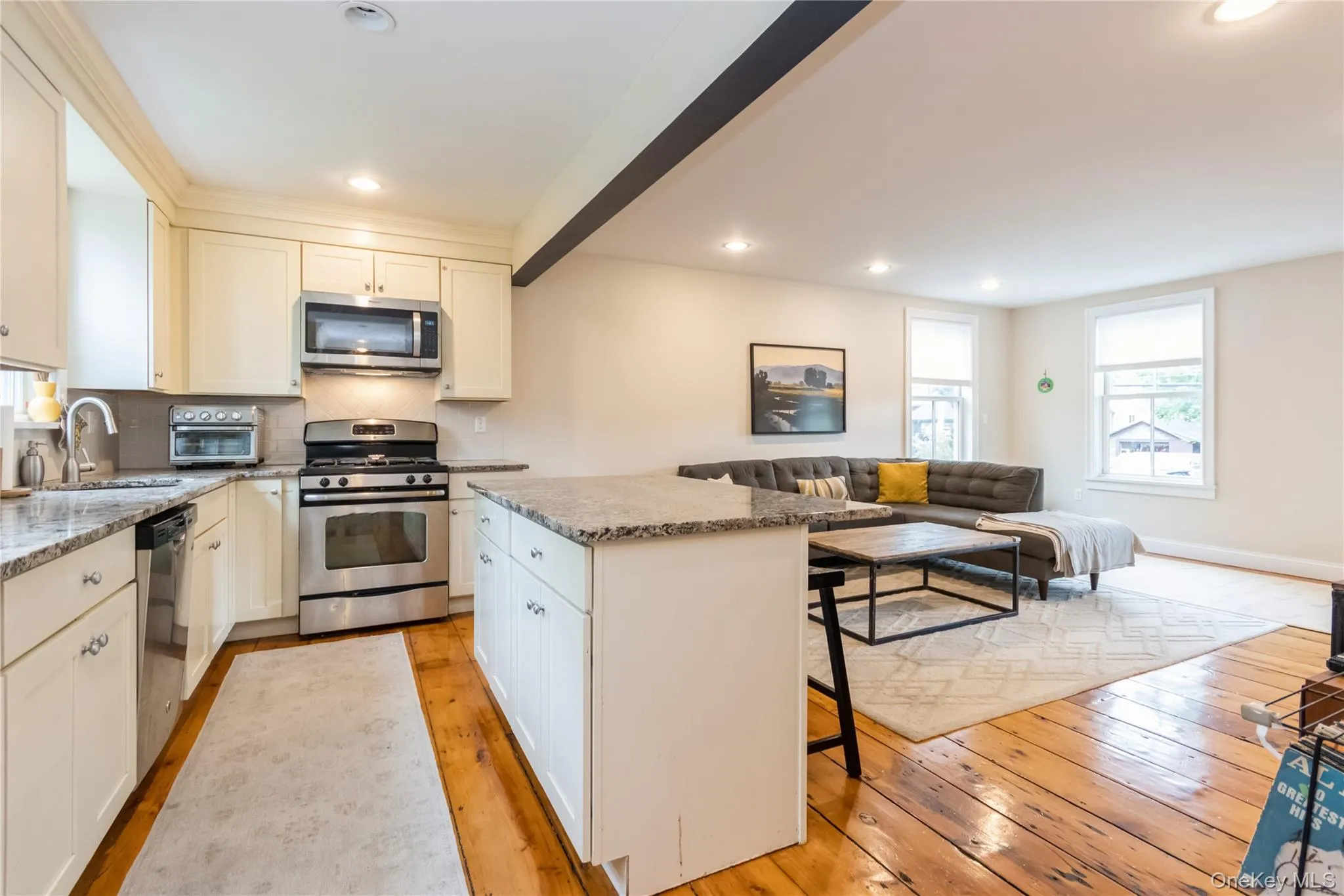Kitchen featuring stainless steel appliances, light wood finished floors, a center island, light stone countertops, and recessed lighting Kitchen featuring stainless steel appliances, light wood finished floors, a center island, light stone countertops, and recessed lighting