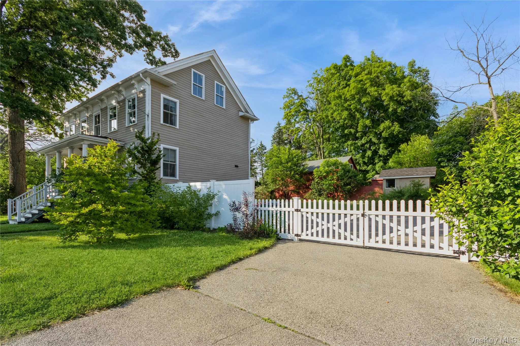 View of side of property featuring a fenced front yard, a gate, and asphalt driveway View of side of property featuring a fenced front yard, a gate, and asphalt driveway