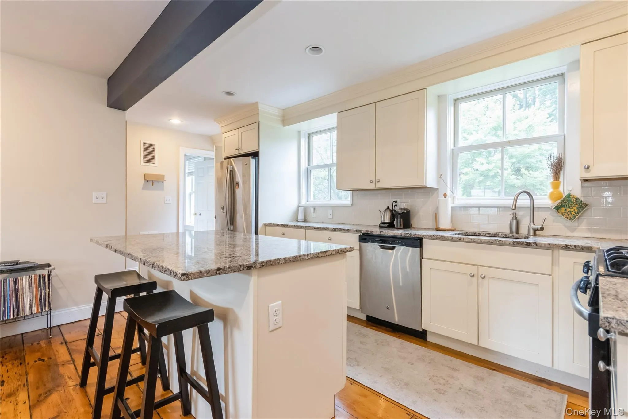 Kitchen with stainless steel appliances, a center island, light wood-type flooring, tasteful backsplash, and light stone countertops Kitchen with stainless steel appliances, a center island, light wood-type flooring, tasteful backsplash, and light stone countertops