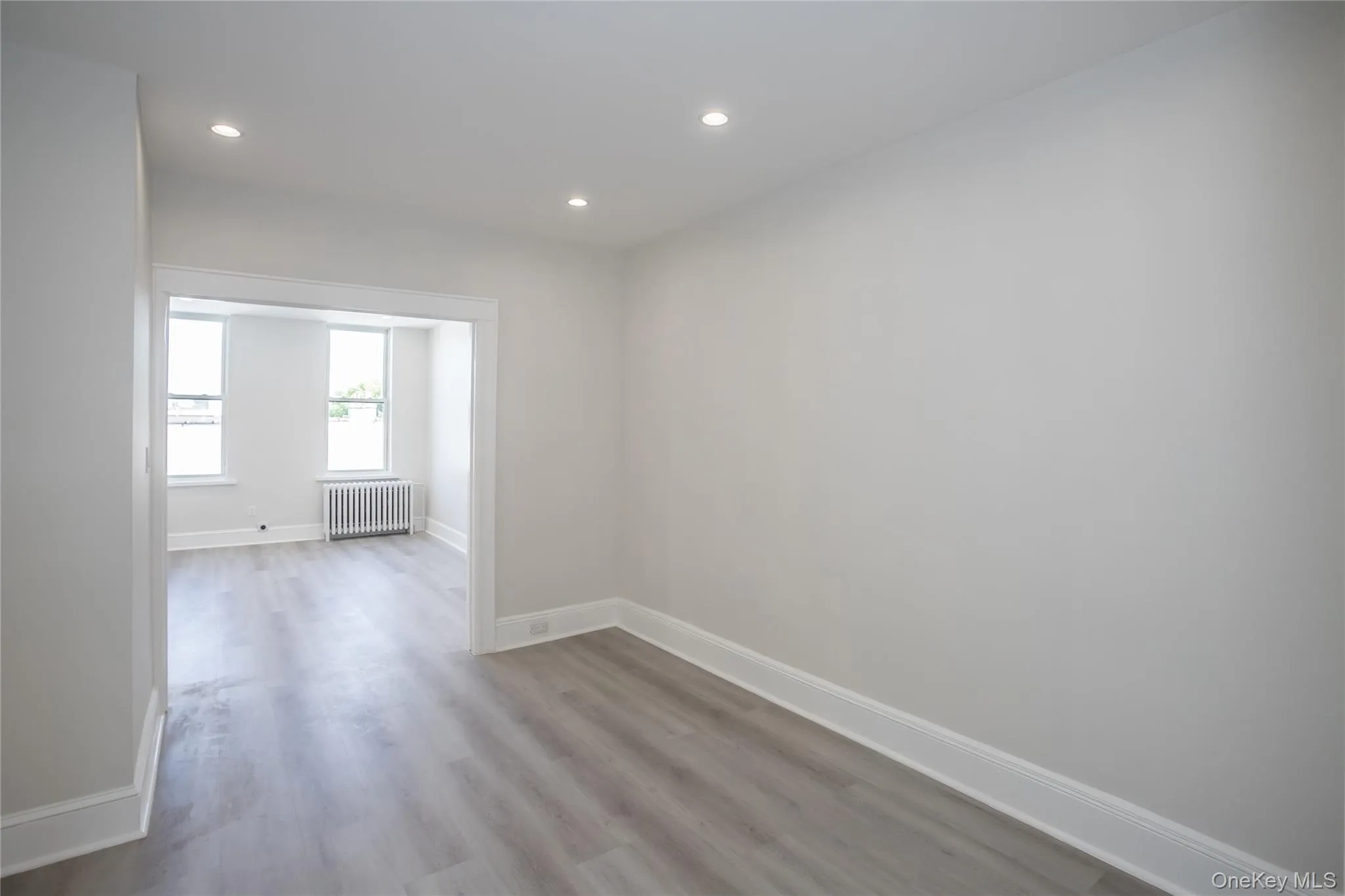 Empty room featuring radiator, wood finished floors, baseboards, and recessed lighting Empty room featuring radiator, wood finished floors, baseboards, and recessed lighting
