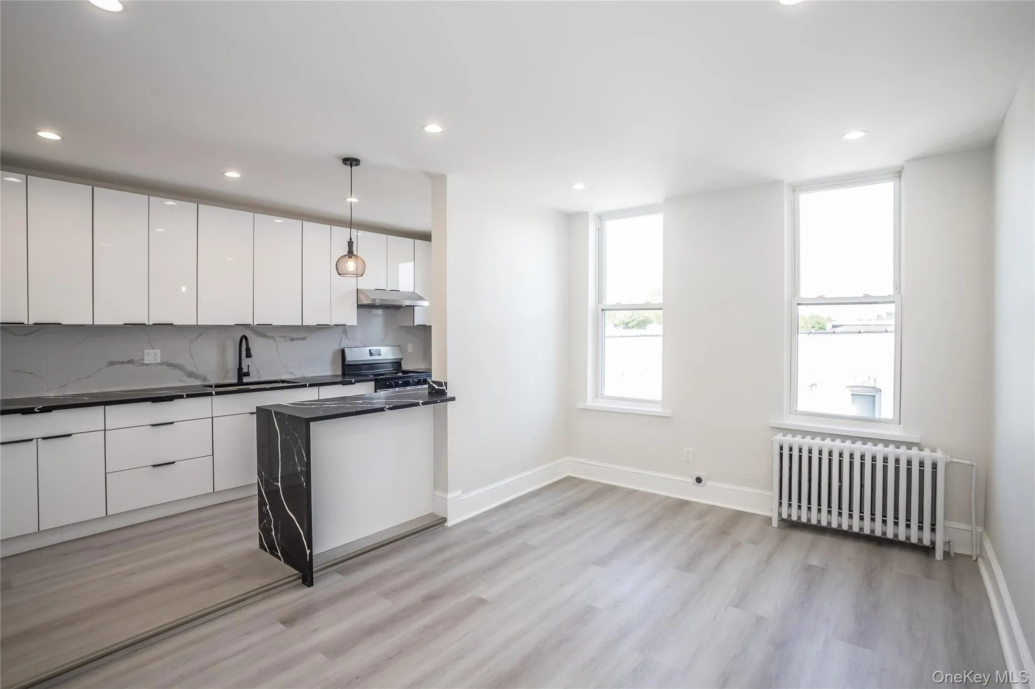 Kitchen with radiator heating unit, stainless steel electric range, modern cabinets, dark countertops, and under cabinet range hood Kitchen with radiator heating unit, stainless steel electric range, modern cabinets, dark countertops, and under cabinet range hood