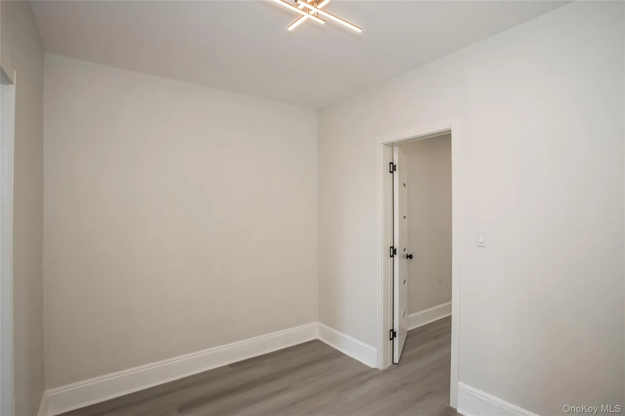 Spare room featuring wood finished floors and baseboards Spare room featuring wood finished floors and baseboards