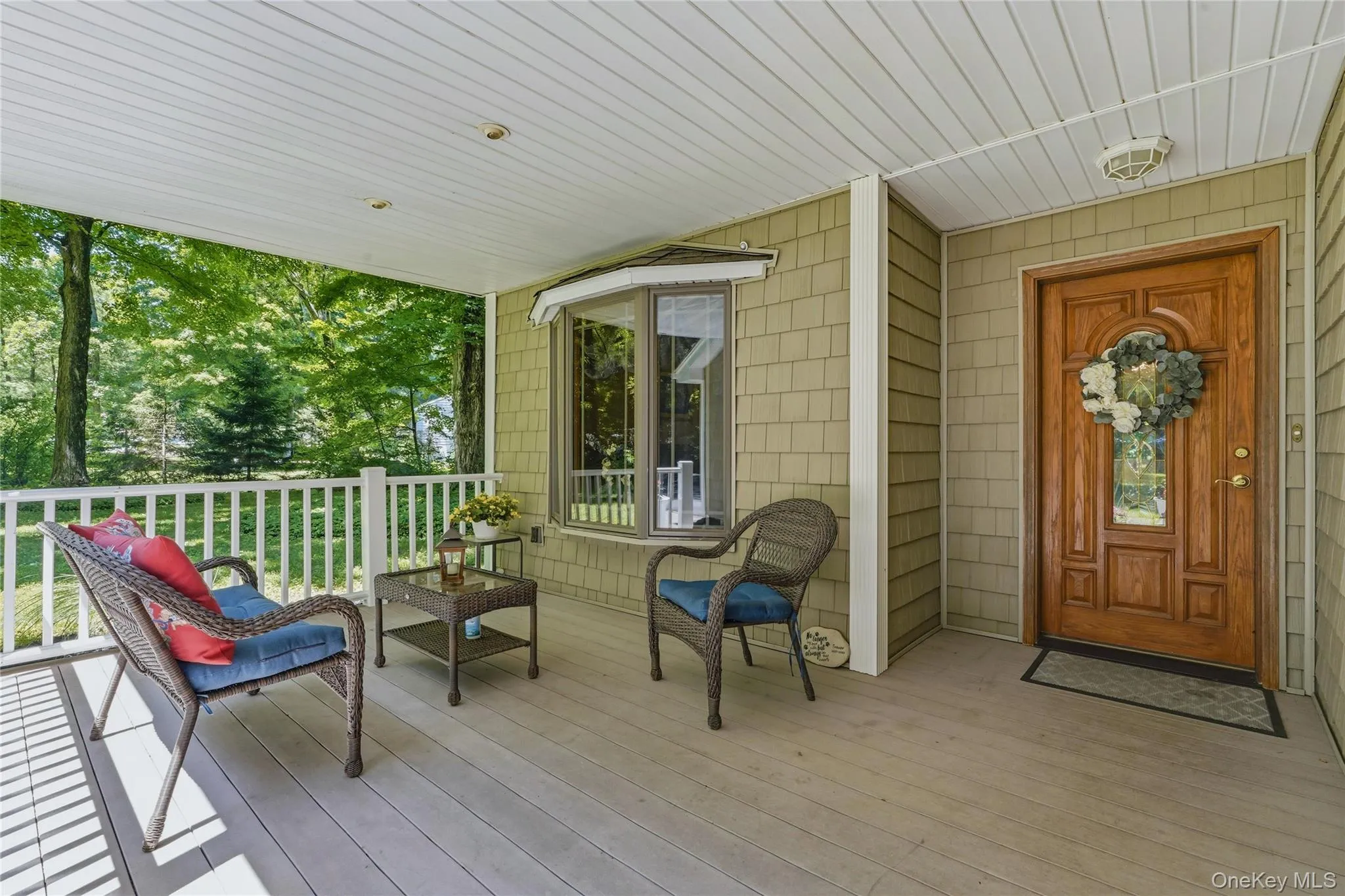 Covered front porch featuring wood-finish flooring, white railing, and a bay window Covered front porch featuring wood-finish flooring, white railing, and a bay window