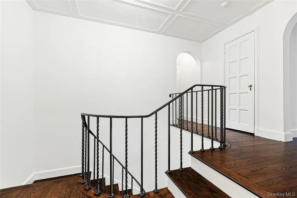 Stairs with arched walkways, wood finished floors, and baseboards Stairs with arched walkways, wood finished floors, and baseboards