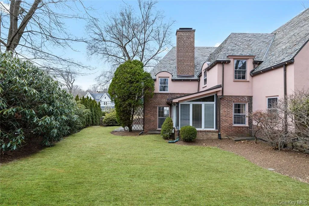 Back of property featuring a lawn, a chimney, brick siding, and stucco siding Back of property featuring a lawn, a chimney, brick siding, and stucco siding