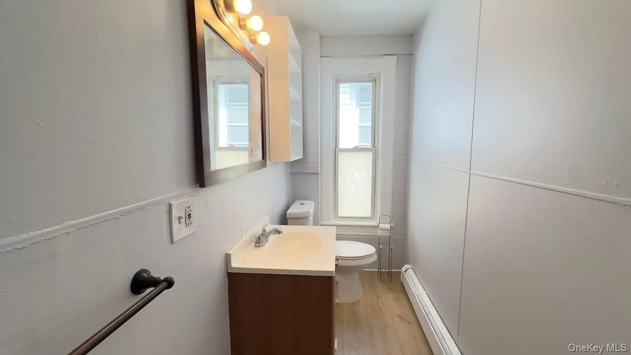 Full bathroom featuring a shower stall, wood like flooring and baseboard heating. Full bathroom featuring a shower stall, wood like flooring and baseboard heating.