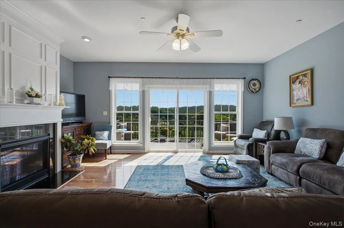Living space featuring a white decorative fireplace surround, a built-in fireplace, hardwood-finish flooring, and a ceiling fan Living space featuring a white decorative fireplace surround, a built-in fireplace, hardwood-finish flooring, and a ceiling fan