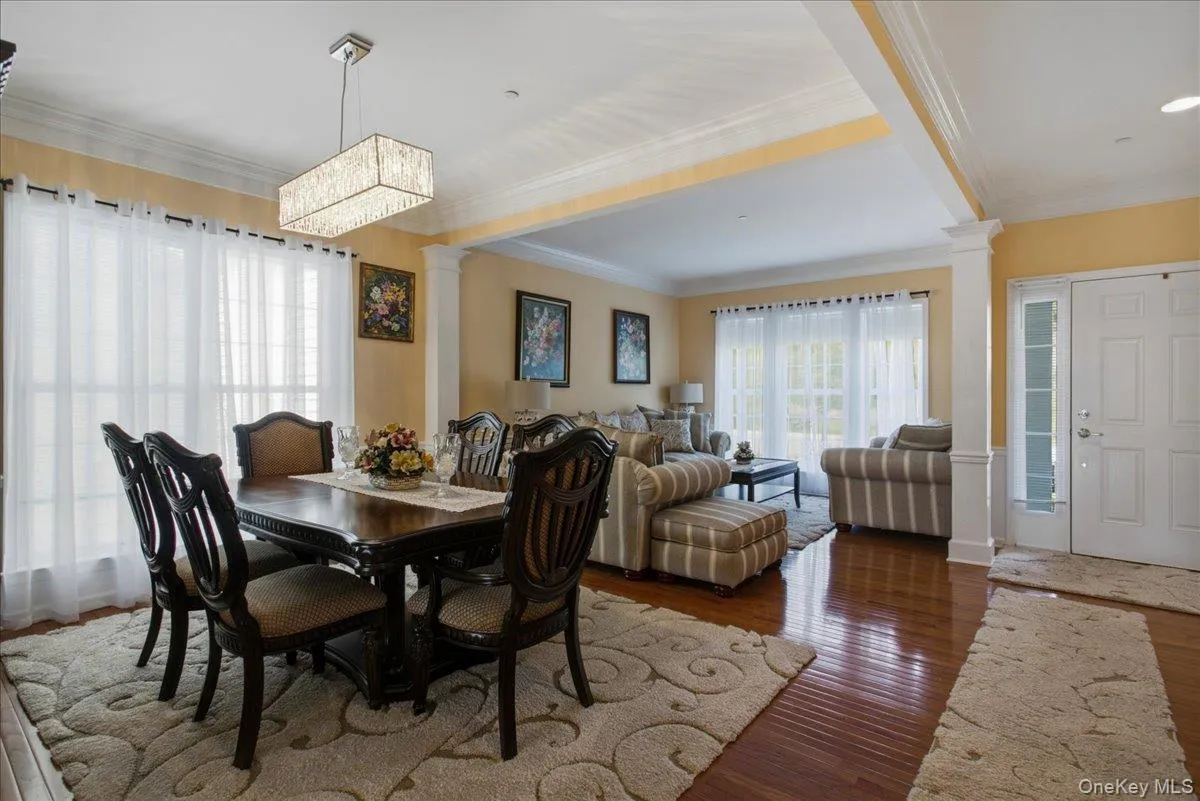Dining area featuring a rectangular crystal chandelier, wood-finish flooring, and crown molding Dining area featuring a rectangular crystal chandelier, wood-finish flooring, and crown molding