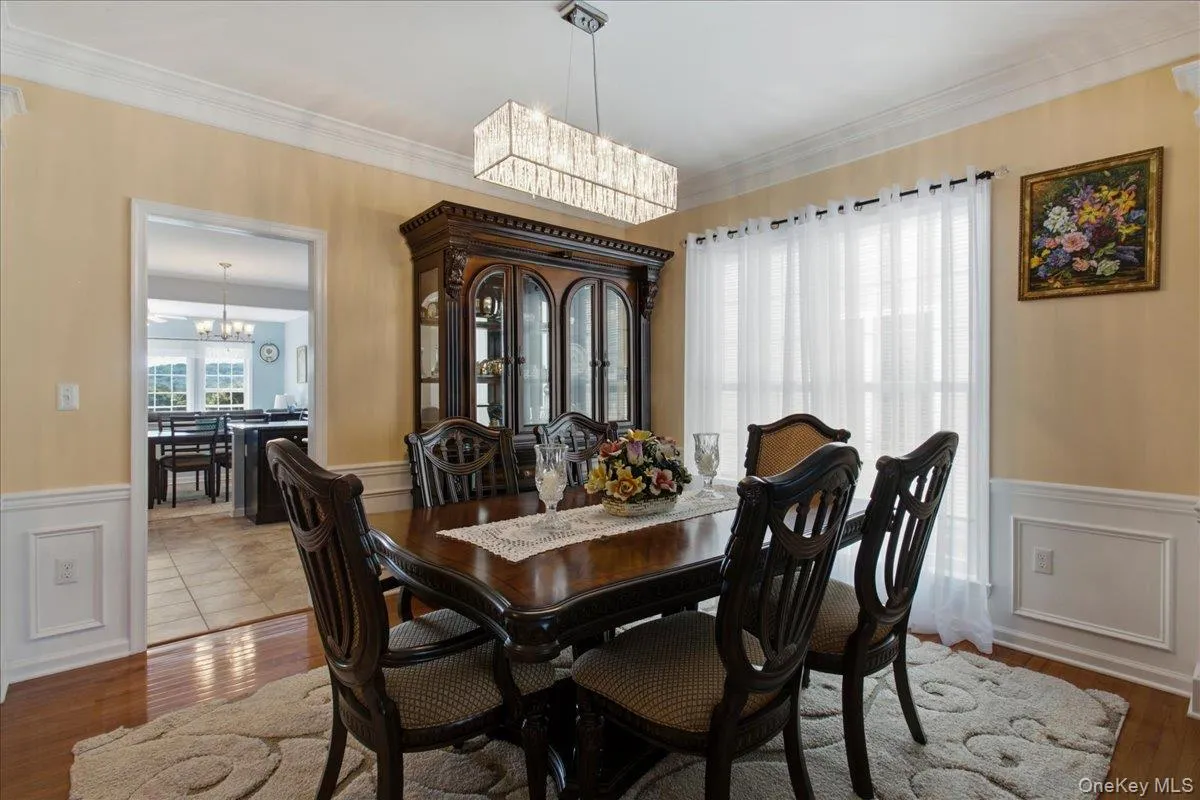 Formal dining space featuring hardwood flooring, wainscoting, crown molding, and a contemporary linear chandelier Formal dining space featuring hardwood flooring, wainscoting, crown molding, and a contemporary linear chandelier