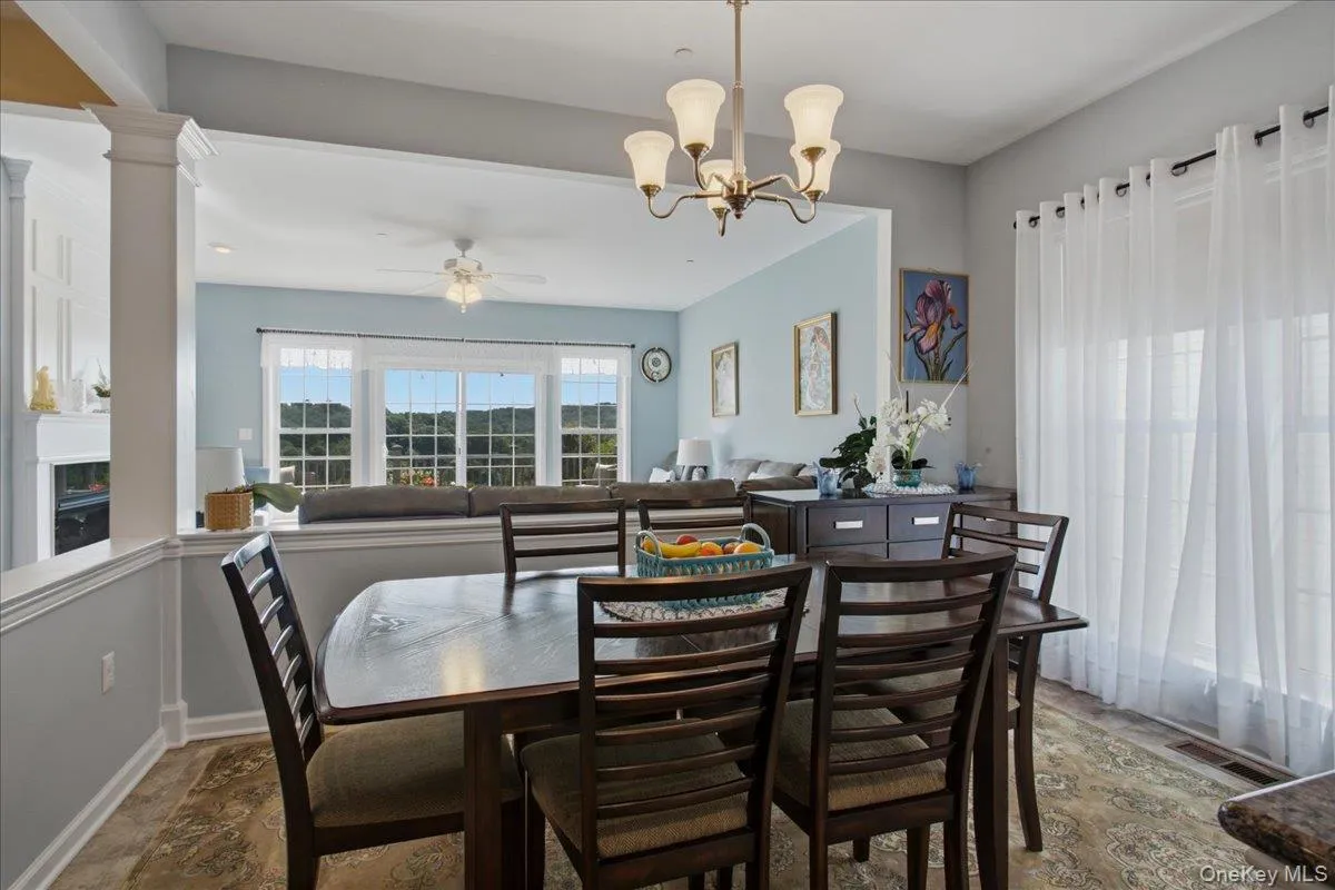 Dining area featuring a bronze-finish chandelier, patterned floor tiling, and bright window treatments Dining area featuring a bronze-finish chandelier, patterned floor tiling, and bright window treatments