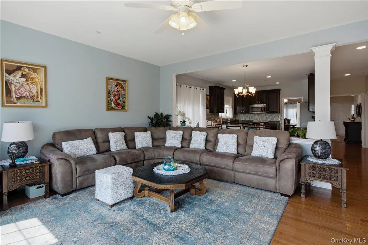 Open-concept living space featuring wood-finish flooring, light blue wall paint, and a ceiling fan with integrated lighting Open-concept living space featuring wood-finish flooring, light blue wall paint, and a ceiling fan with integrated lighting