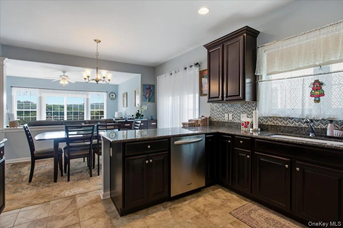 Kitchen featuring dark wood-finish cabinetry, granite countertops, and a tiled backsplash Kitchen featuring dark wood-finish cabinetry, granite countertops, and a tiled backsplash