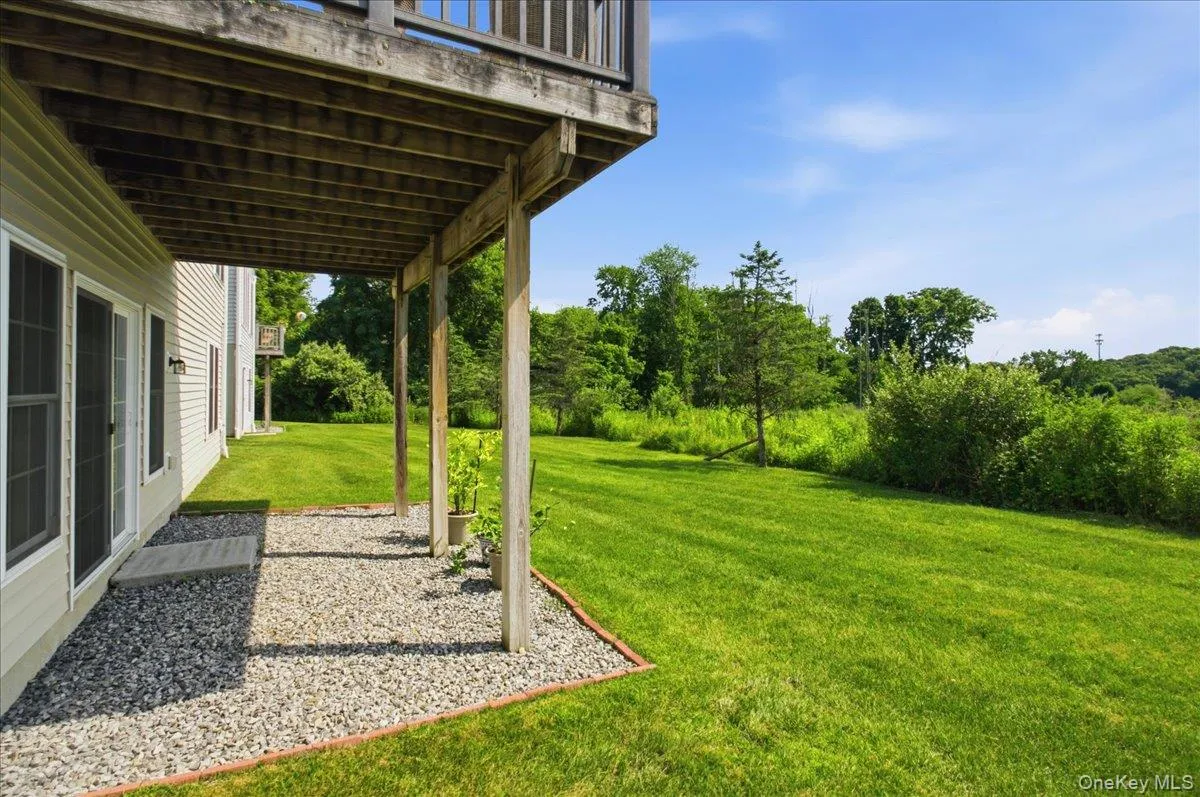 Lower-level patio with gravel hardscaping and a concrete stepping stone, providing direct access to a grassy outdoor area Lower-level patio with gravel hardscaping and a concrete stepping stone, providing direct access to a grassy outdoor area