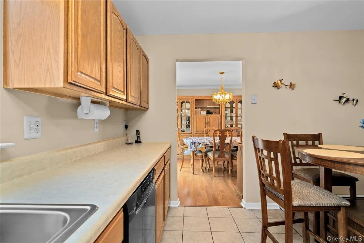 Kitchen featuring nice wood-finish cabinetry, black appliances including a refrigerator and range, a stainless steel sink, and light-toned countertops Kitchen featuring nice wood-finish cabinetry, black appliances including a refrigerator and range, a stainless steel sink, and light-toned countertops