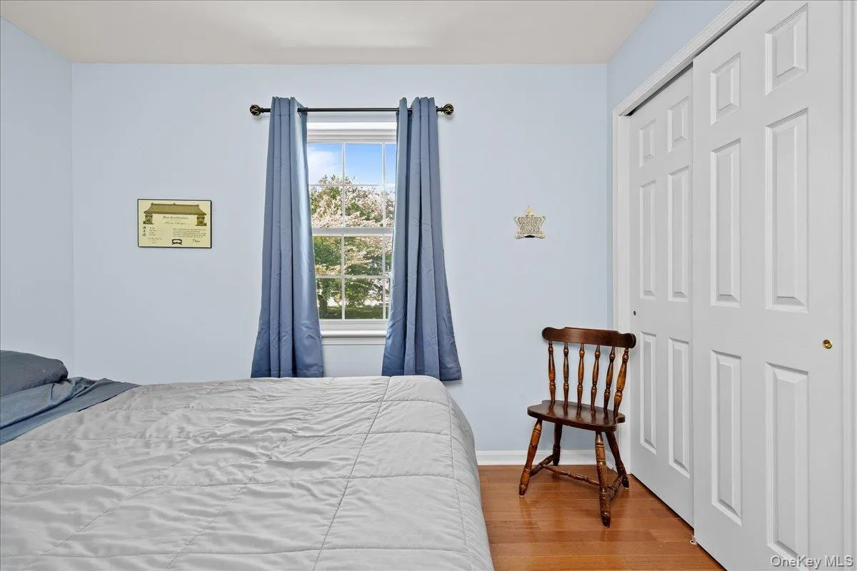 Bedroom 2 featuring a large window with natural light, a bi-fold closet with paneled doors, and wood-finish flooring Bedroom 2 featuring a large window with natural light, a bi-fold closet with paneled doors, and wood-finish flooring