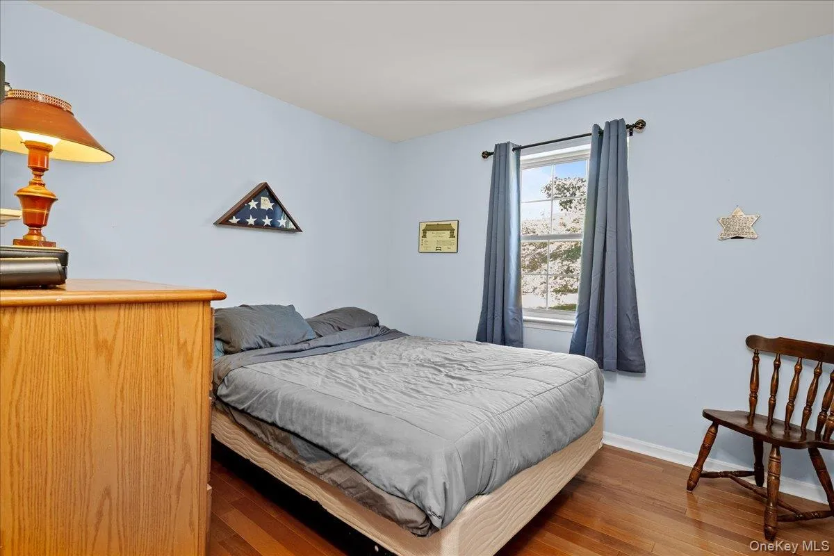 Bedroom 2 featuring light blue walls, wood-finish flooring, and a window with dark curtains Bedroom 2 featuring light blue walls, wood-finish flooring, and a window with dark curtains