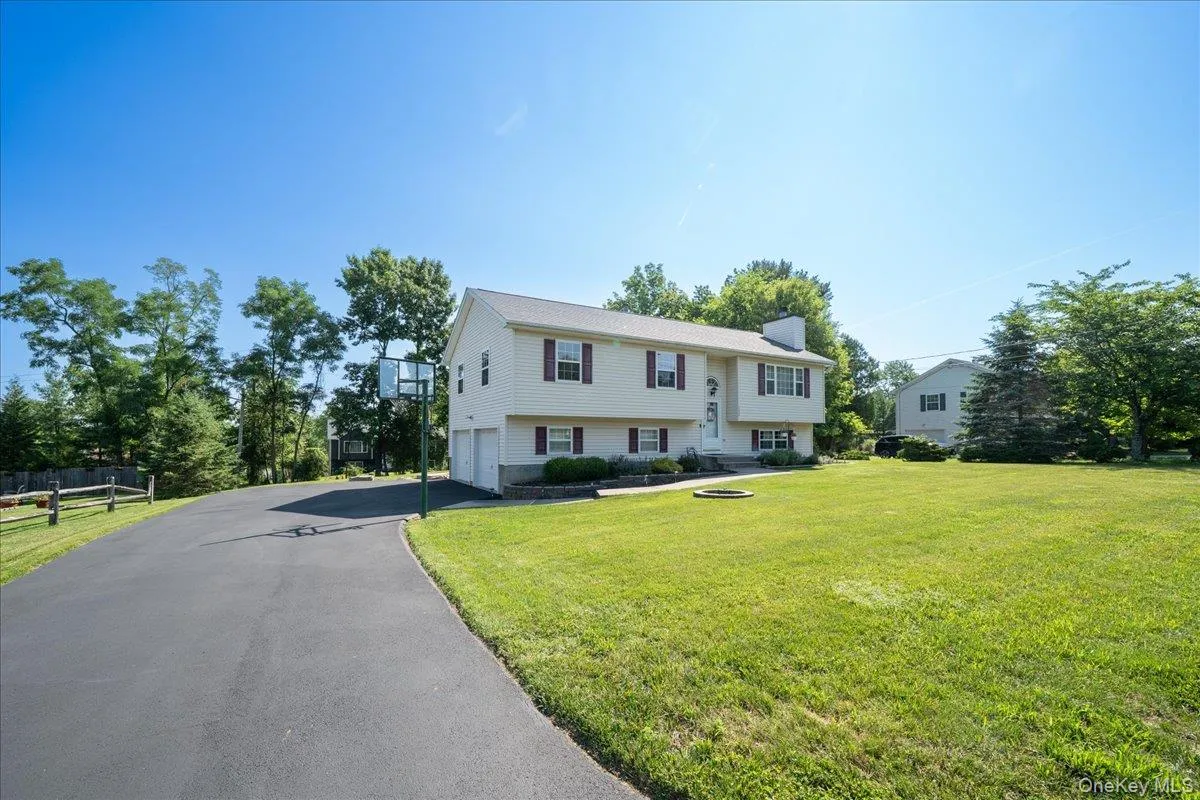 Two-story residence featuring a cream-colored exterior, an attached 2 car garage, and a paved driveway Two-story residence featuring a cream-colored exterior, an attached 2 car garage, and a paved driveway
