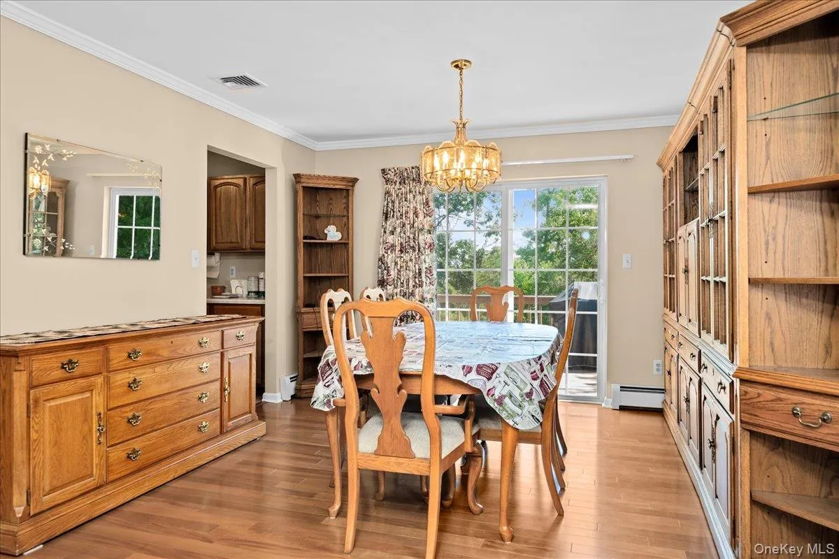 Dining room area with wood-finish flooring, a traditional chandelier, and crown molding Dining room area with wood-finish flooring, a traditional chandelier, and crown molding