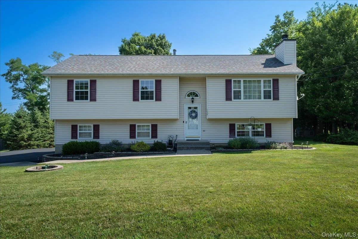 Bi-level residence featuring light-colored siding, a two-car garage, and dark-colored window shutters Bi-level residence featuring light-colored siding, a two-car garage, and dark-colored window shutters
