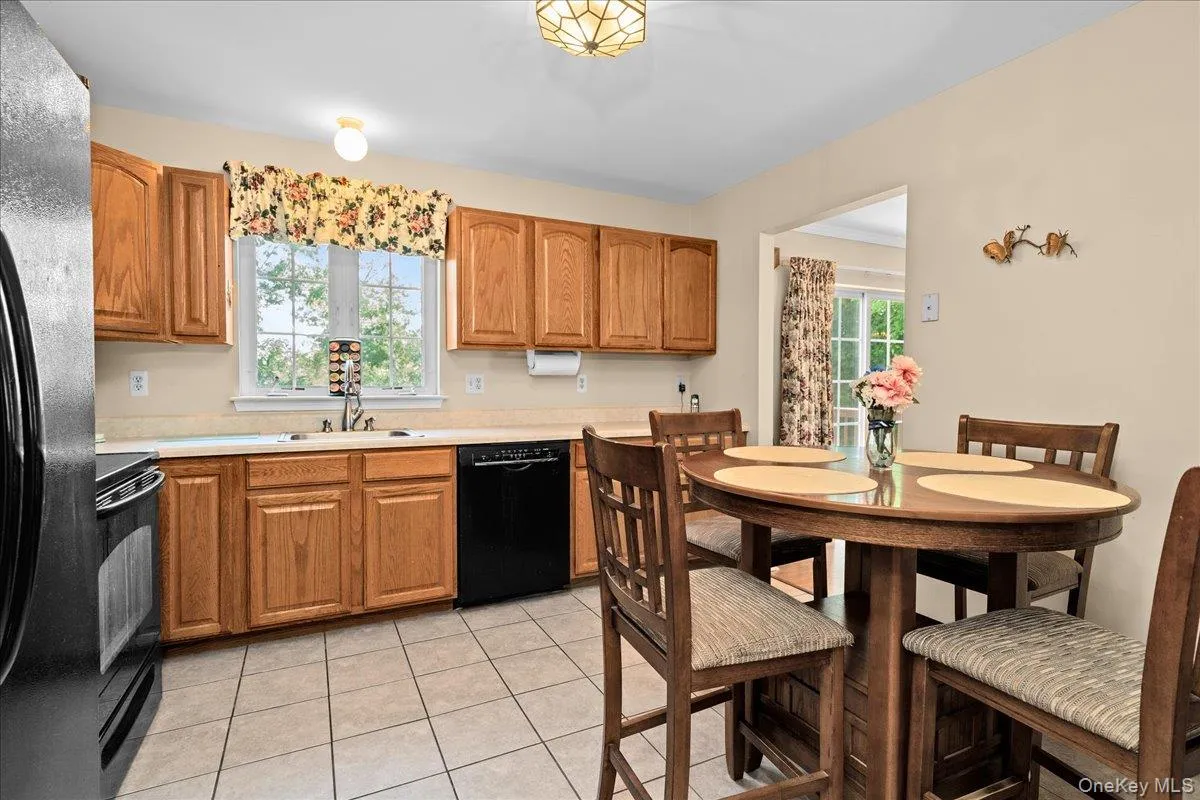 Kitchen featuring a window above the sink, wood cabinetry, countertops, and a black dishwasher Kitchen featuring a window above the sink, wood cabinetry, countertops, and a black dishwasher