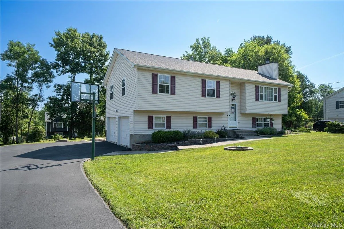 Bi-level residence featuring light-colored siding, a two-car garage, and dark-colored window shutters Bi-level residence featuring light-colored siding, a two-car garage, and dark-colored window shutters