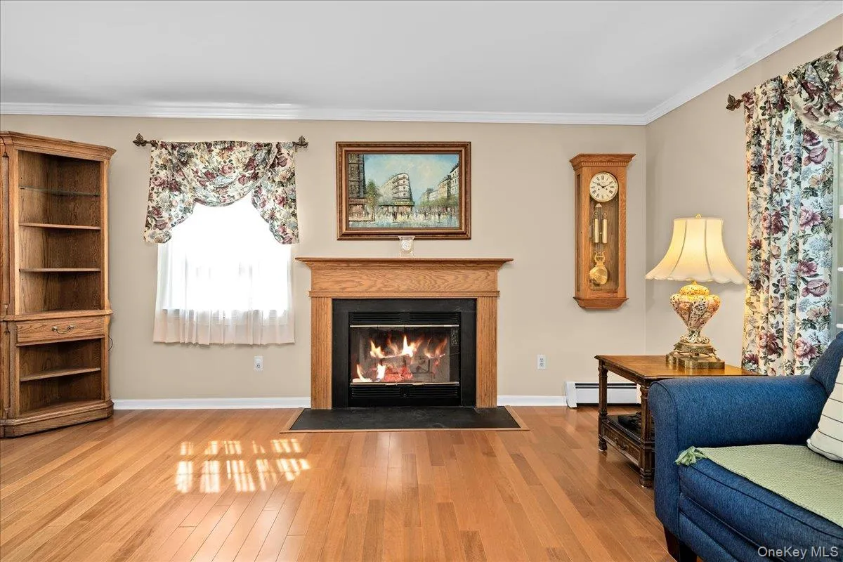 Living room area featuring a wood burning fireplace with a wood mantle, a black hearth, and wood-finish flooring Living room area featuring a wood burning fireplace with a wood mantle, a black hearth, and wood-finish flooring