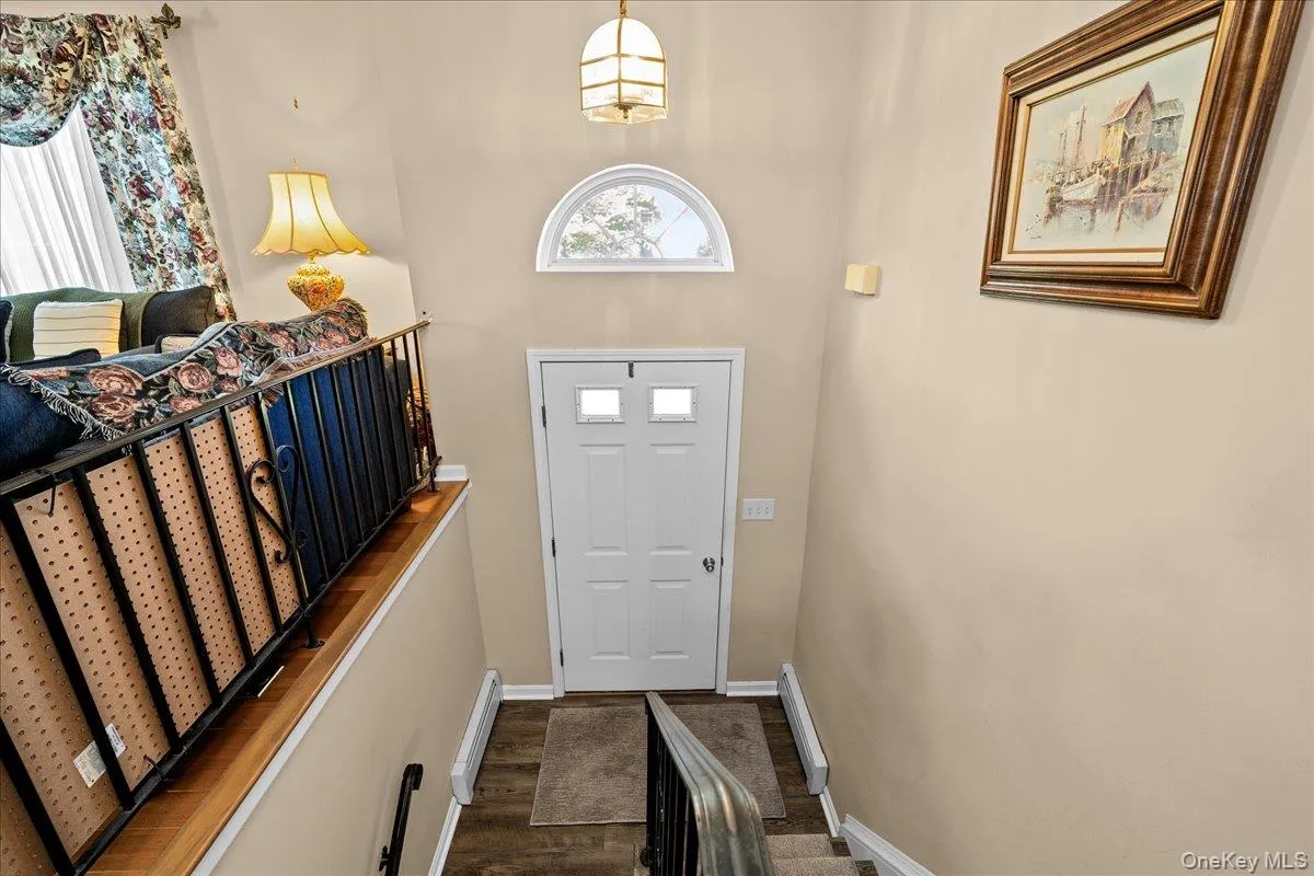 Entry featuring a carpeted staircase with white risers and a black metal railing Entry featuring a carpeted staircase with white risers and a black metal railing