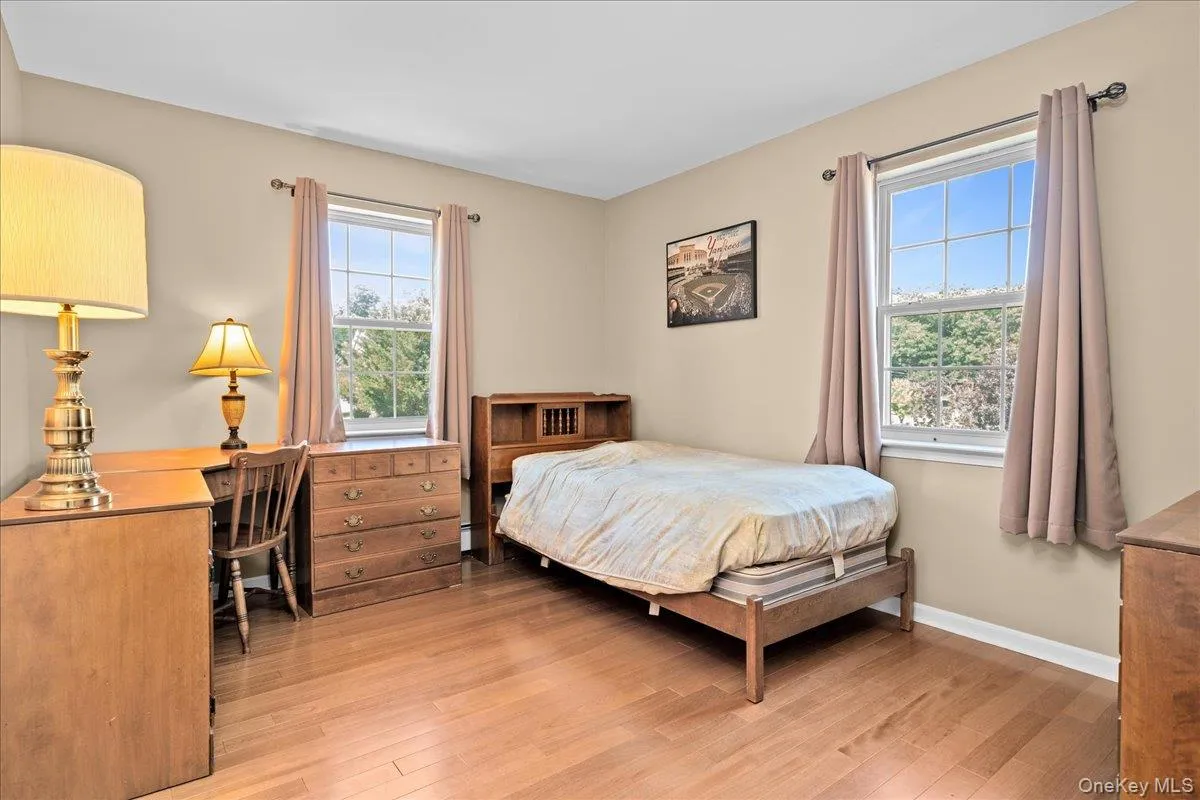 Bedroom 3, a light-filled room featuring two windows, wood-finish flooring, and neutral wall tones Bedroom 3, a light-filled room featuring two windows, wood-finish flooring, and neutral wall tones