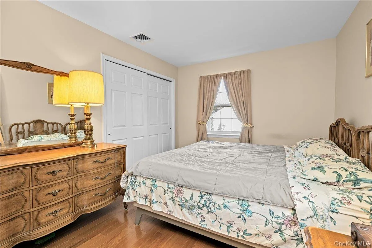 Bedroom 1 featuring wood-finish flooring, a window with natural light, and sliding closet doors Bedroom 1 featuring wood-finish flooring, a window with natural light, and sliding closet doors