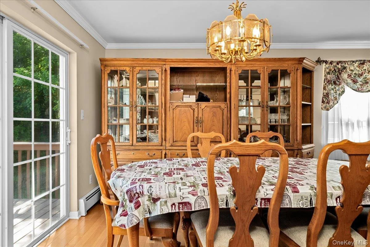 Dining room area featuring wood-finish flooring, a built-in display cabinet with glass doors, and a brass-tone chandelier Dining room area featuring wood-finish flooring, a built-in display cabinet with glass doors, and a brass-tone chandelier