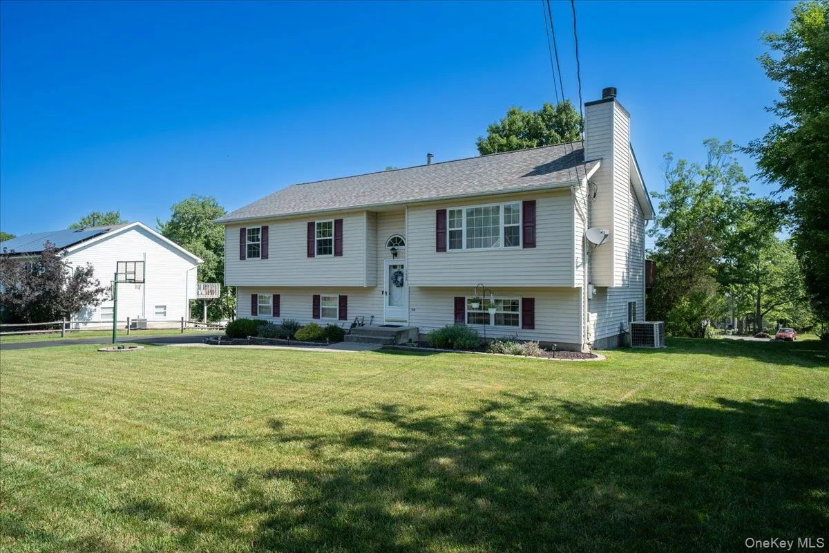 Bi-level residence featuring light-colored siding, a two-car garage, and dark-colored window shutters Bi-level residence featuring light-colored siding, a two-car garage, and dark-colored window shutters