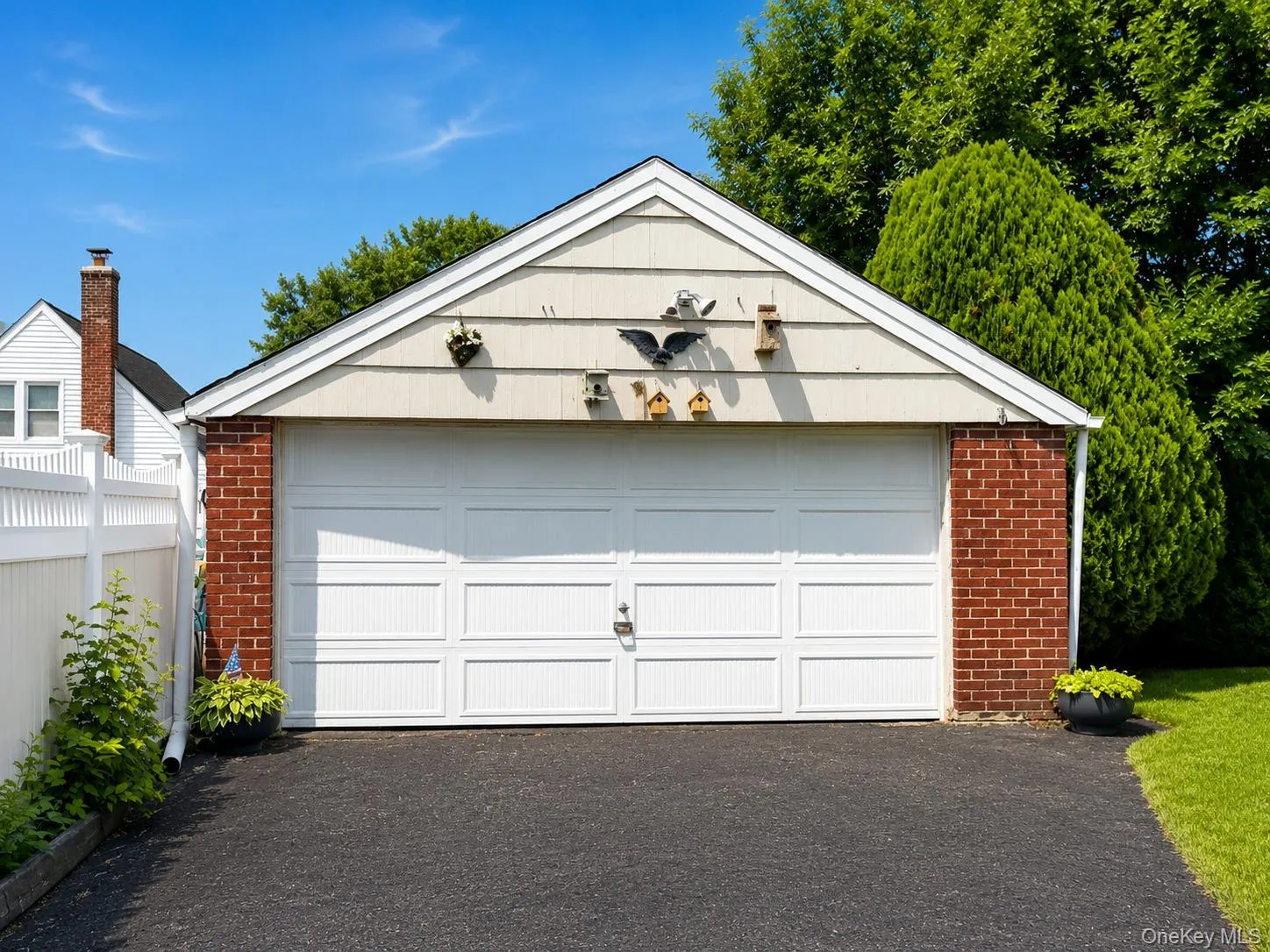 Detached two-car garage featuring a white panel door, brick pillars, and light-colored siding Detached two-car garage featuring a white panel door, brick pillars, and light-colored siding