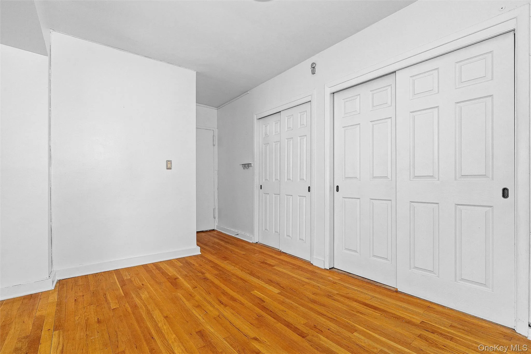 Unfurnished bedroom featuring two closets and light hardwood / wood-style floors Unfurnished bedroom featuring two closets and light hardwood / wood-style floors