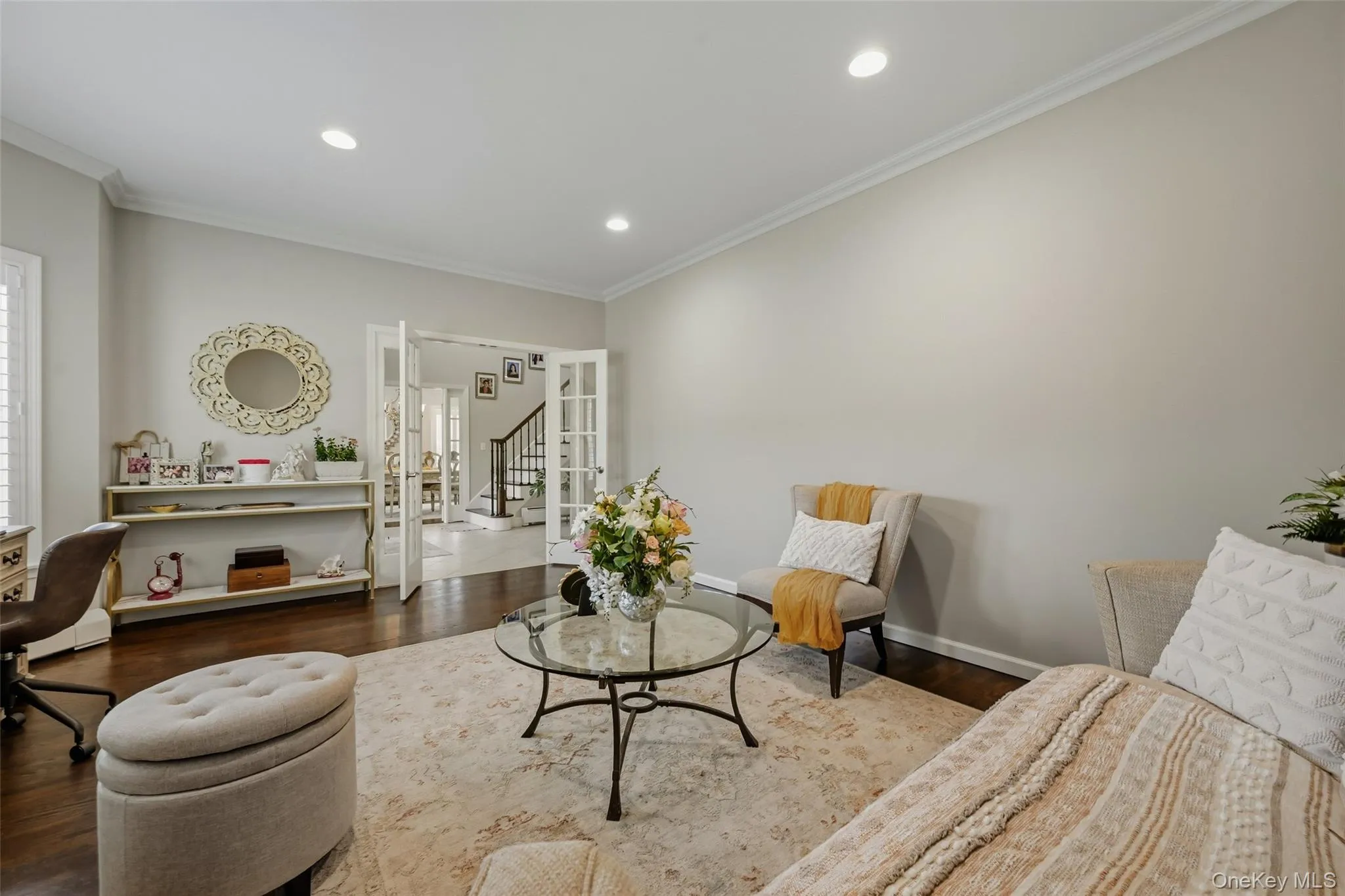 Versatile living space featuring dark wood-finish flooring, with recessed lighting, and white crown molding Versatile living space featuring dark wood-finish flooring, with recessed lighting, and white crown molding