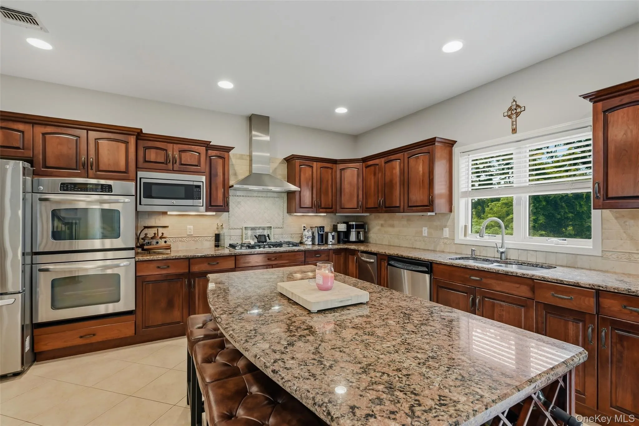 Kitchen featuring a large island with granite countertops, wood cabinetry, stainless steel appliances, and recessed lighting Kitchen featuring a large island with granite countertops, wood cabinetry, stainless steel appliances, and recessed lighting