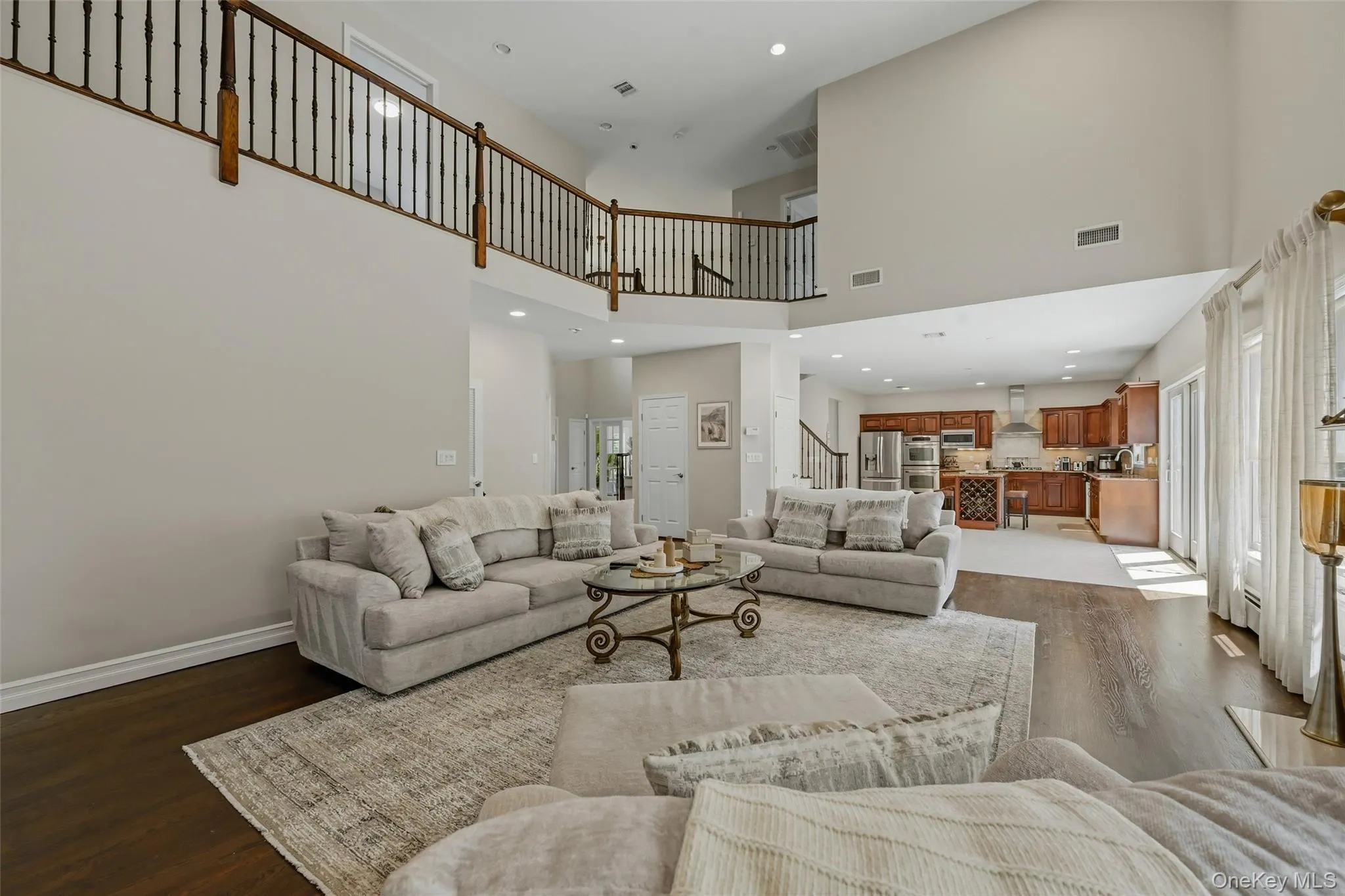 Two-story living area featuring dark wood-finish flooring, a wood and iron baluster railing, and recessed lighting Two-story living area featuring dark wood-finish flooring, a wood and iron baluster railing, and recessed lighting