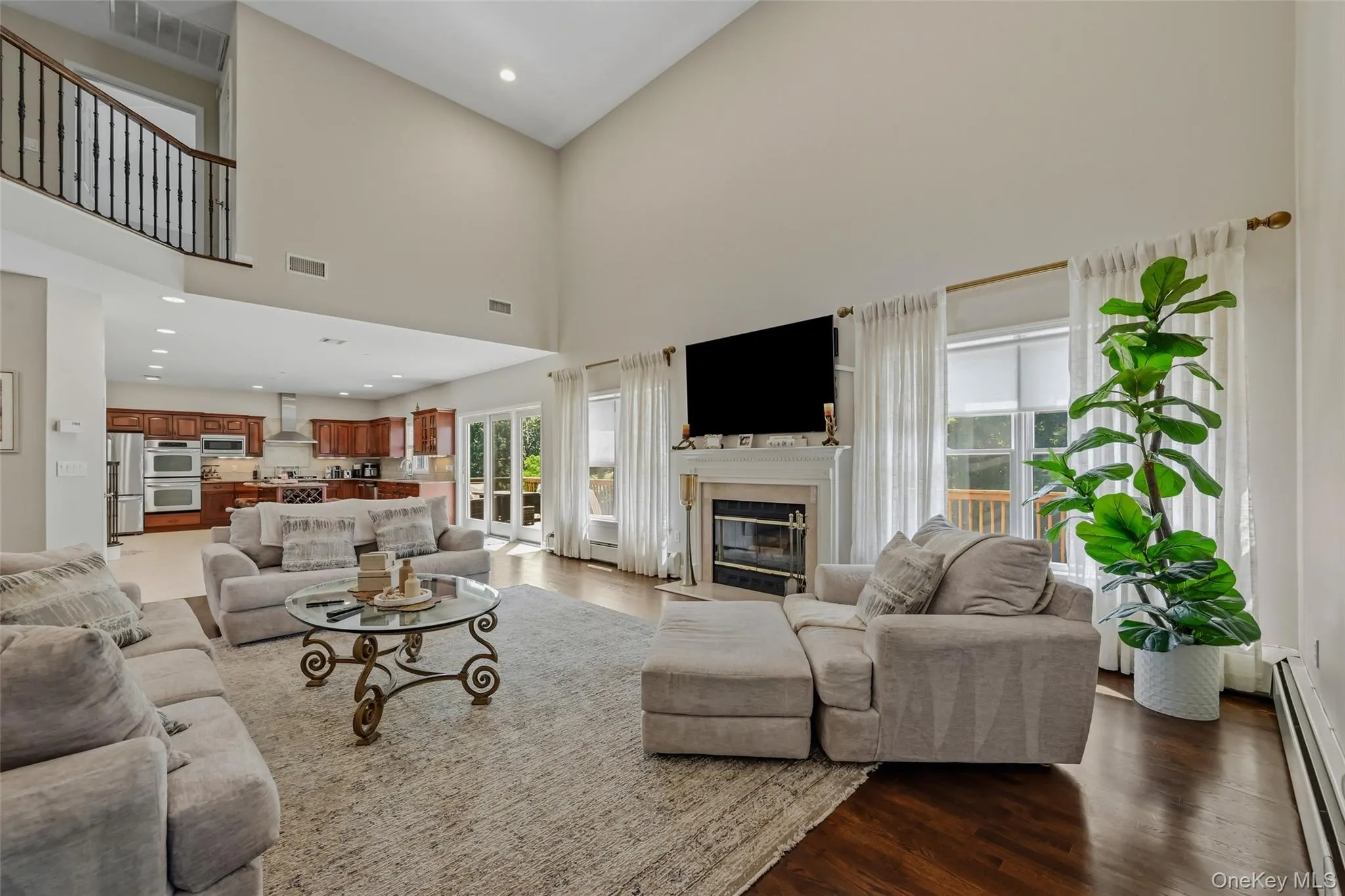 Two-story living area featuring a fireplace, dark wood-finish flooring, and expansive windows Two-story living area featuring a fireplace, dark wood-finish flooring, and expansive windows