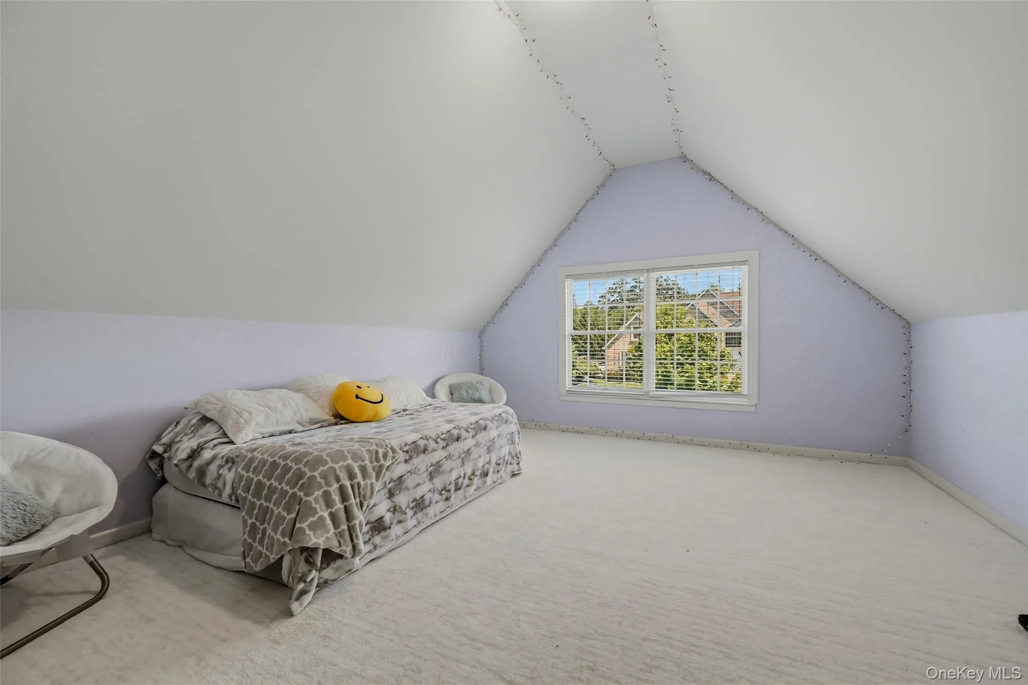 Carpeted room with sloped ceilings and a single window featuring white blinds Carpeted room with sloped ceilings and a single window featuring white blinds