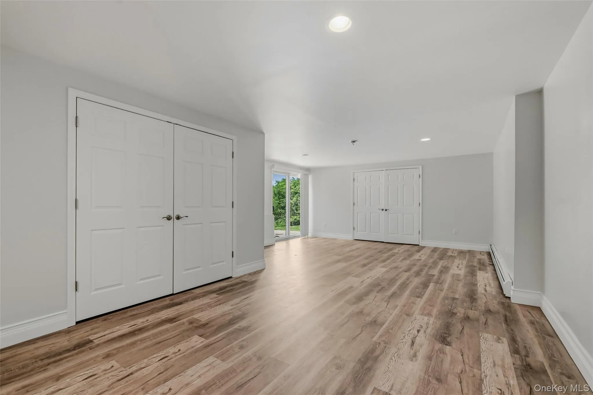 Spacious room featuring wood-finish flooring, neutral walls, and white trim Spacious room featuring wood-finish flooring, neutral walls, and white trim