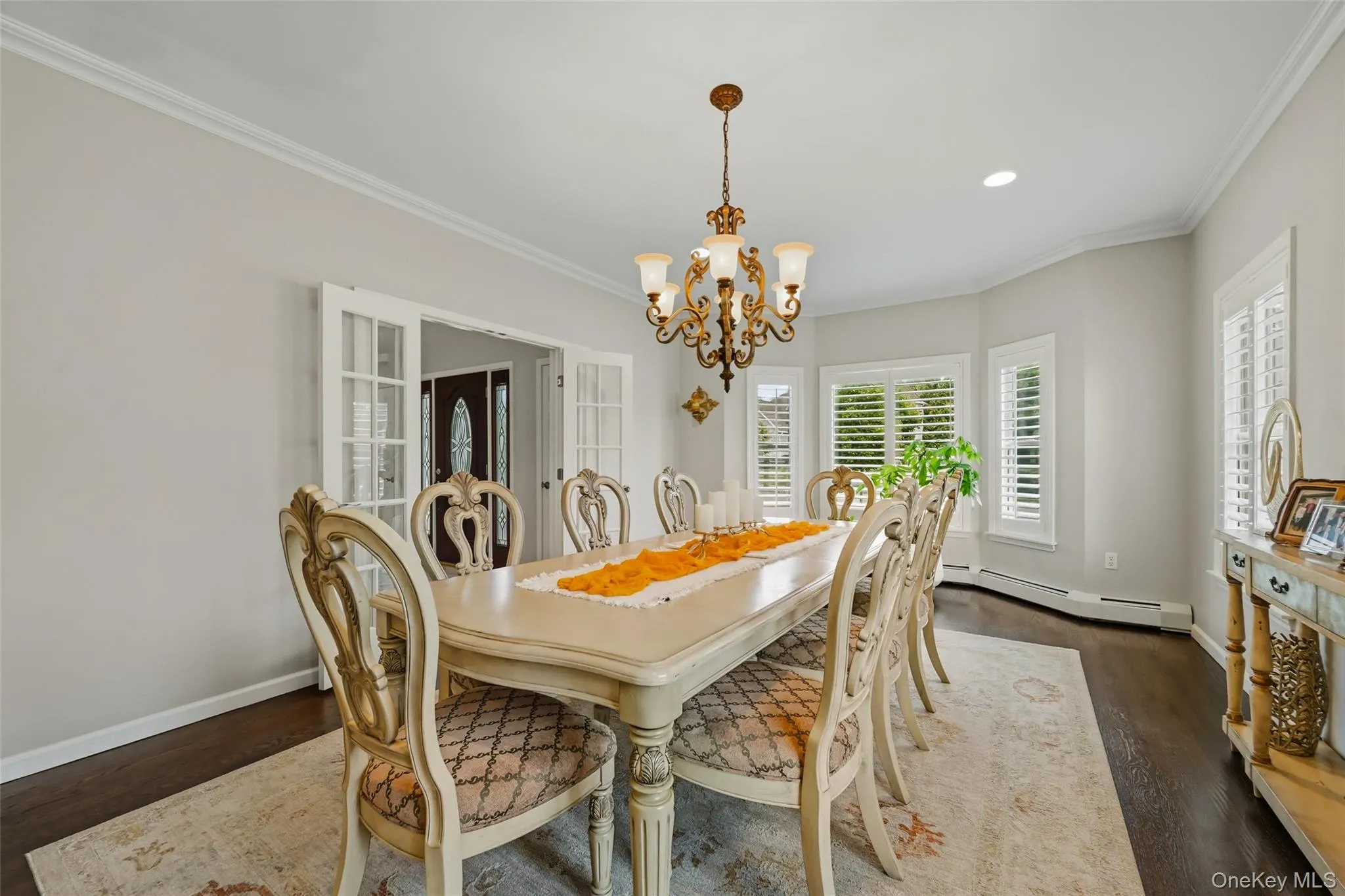 Dining area featuring dark wood-finish flooring, light walls, and white crown molding Dining area featuring dark wood-finish flooring, light walls, and white crown molding