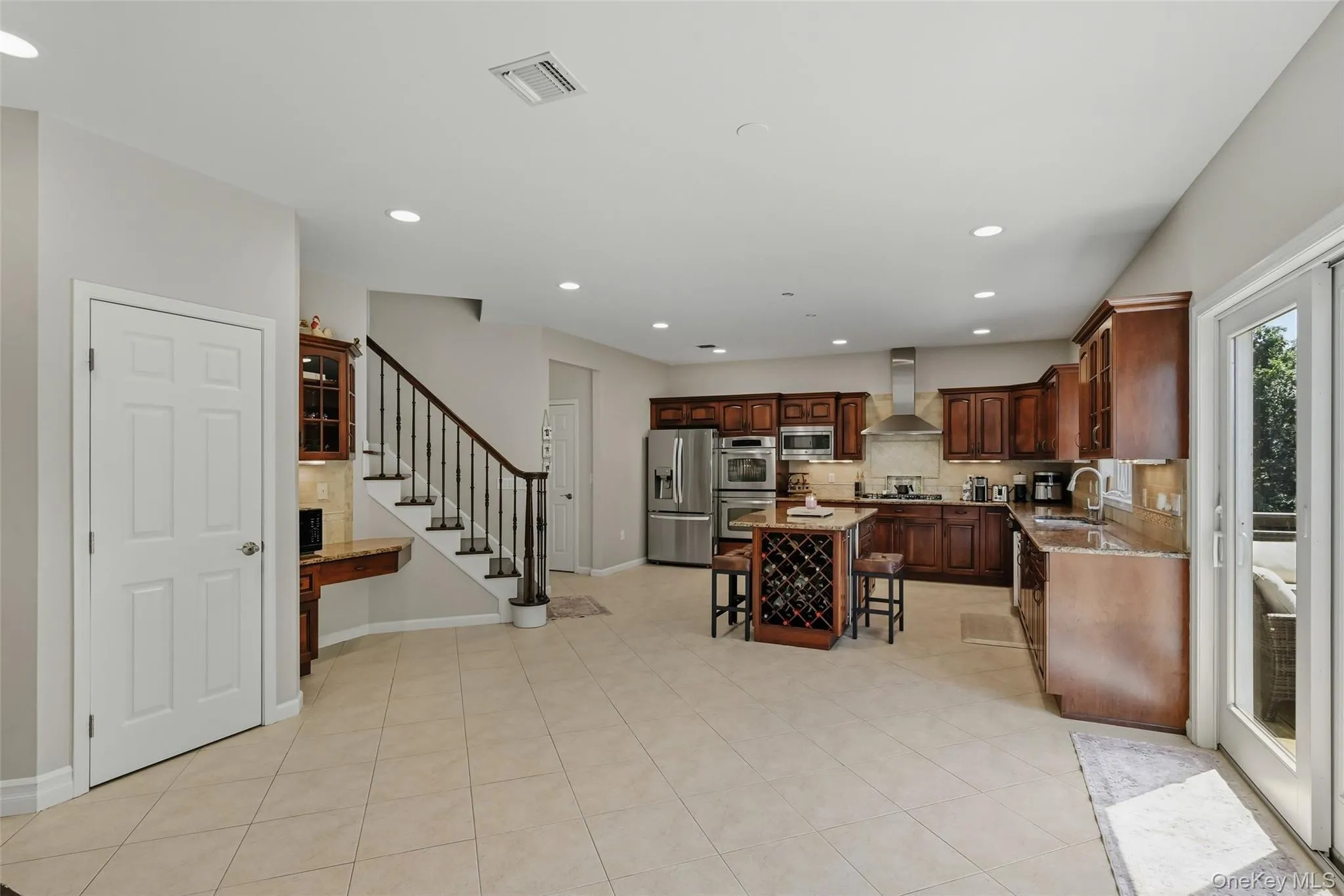 Spacious open-concept kitchen featuring wood cabinetry, stainless steel appliances, and a central island with integrated wine storage Spacious open-concept kitchen featuring wood cabinetry, stainless steel appliances, and a central island with integrated wine storage