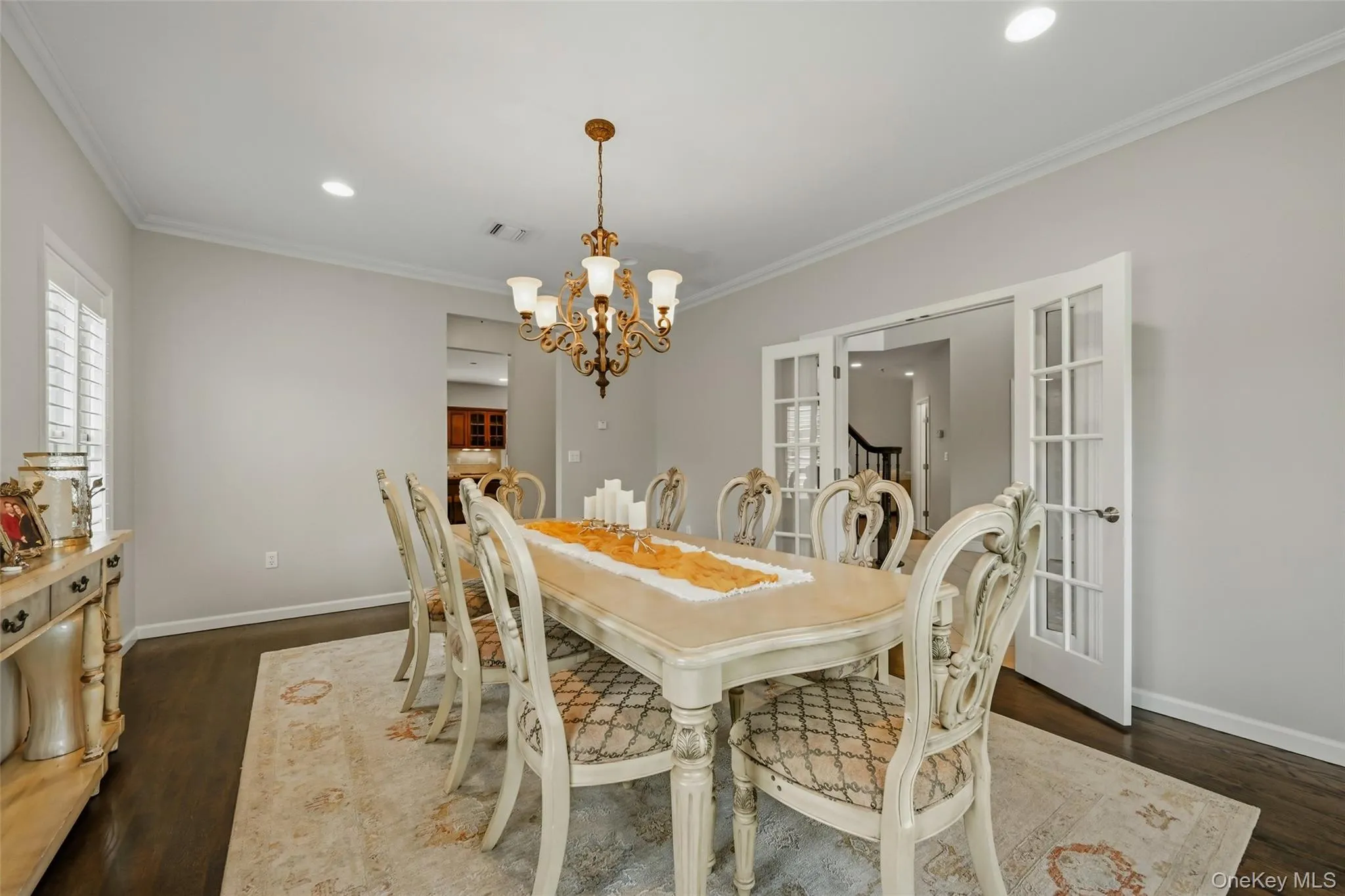 Formal dining room featuring dark wood-finish flooring, a decorative chandelier, recessed lighting, and white crown molding Formal dining room featuring dark wood-finish flooring, a decorative chandelier, recessed lighting, and white crown molding