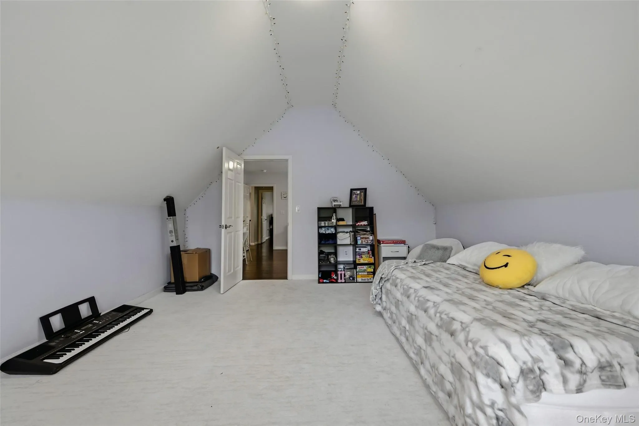 Room with sloped ceilings, light-colored carpeting, and a white interior door Room with sloped ceilings, light-colored carpeting, and a white interior door